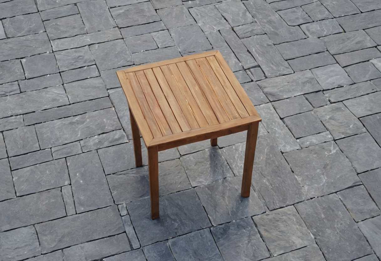 Small square slatted wooden patio table on gray stone paving, viewed from an elevated angle.